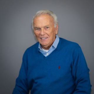 Older man with grey hair wearing a sky-blue sweater