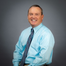 Man wearing a light blue shirt and blue patterned tie