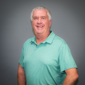 Older man with grey hair wearing a teal shirt