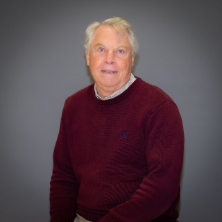 Older man with grey hair wearing a maroon sweater