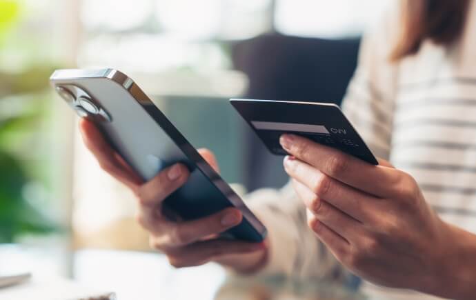 close-up of hands holding a smartphone and credit card 